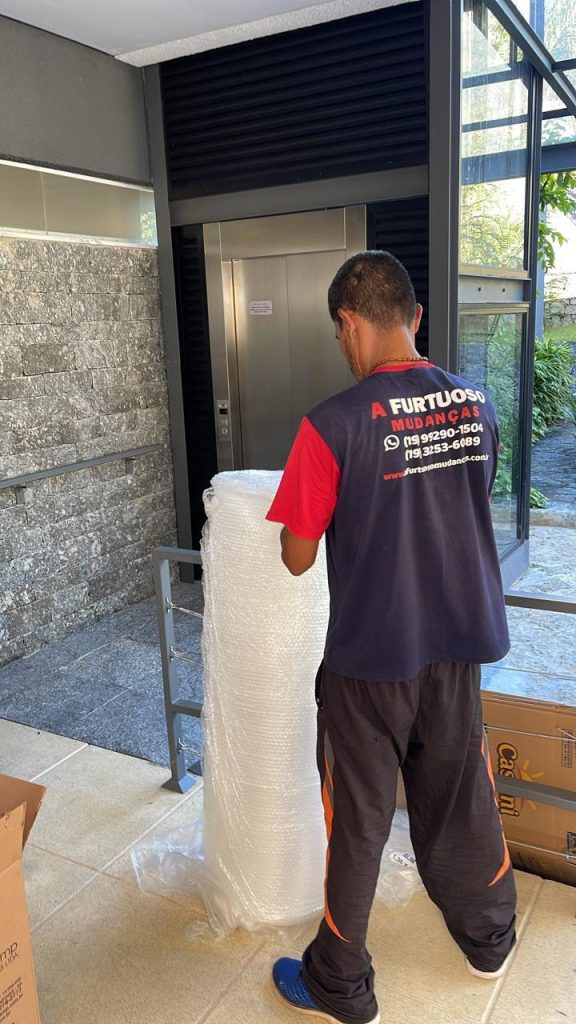 Profissional da A. Furtuoso com material de proteção próximo ao elevador