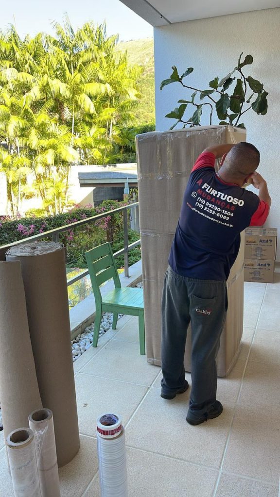 Profissional da A. Furtuoso embalando móvel alto com material de proteção